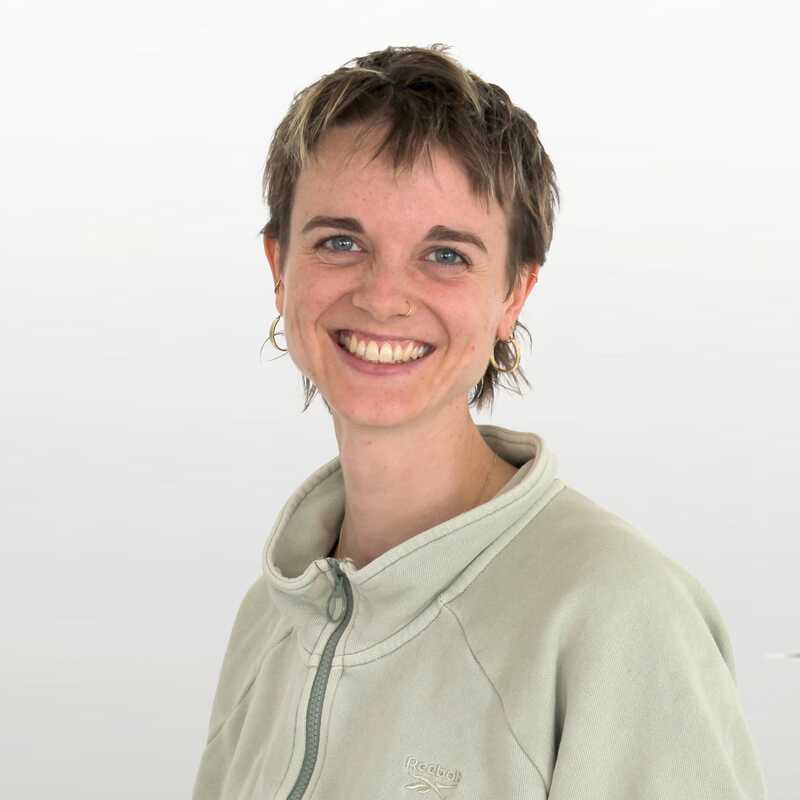 Junge Frau mit kurzen, hellen Haaren lächelt in die Kamera