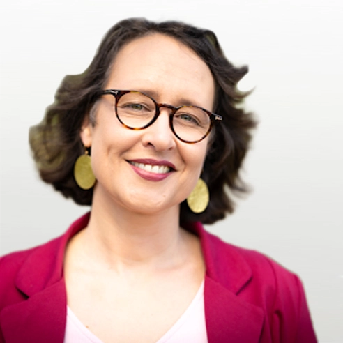 Portätbild von Ulrike Fechner. Frau mit dunklen, kürzeren Haarenlächelt in die Kamera. Sie trägt eine braune Brille und goldene Ohringe.