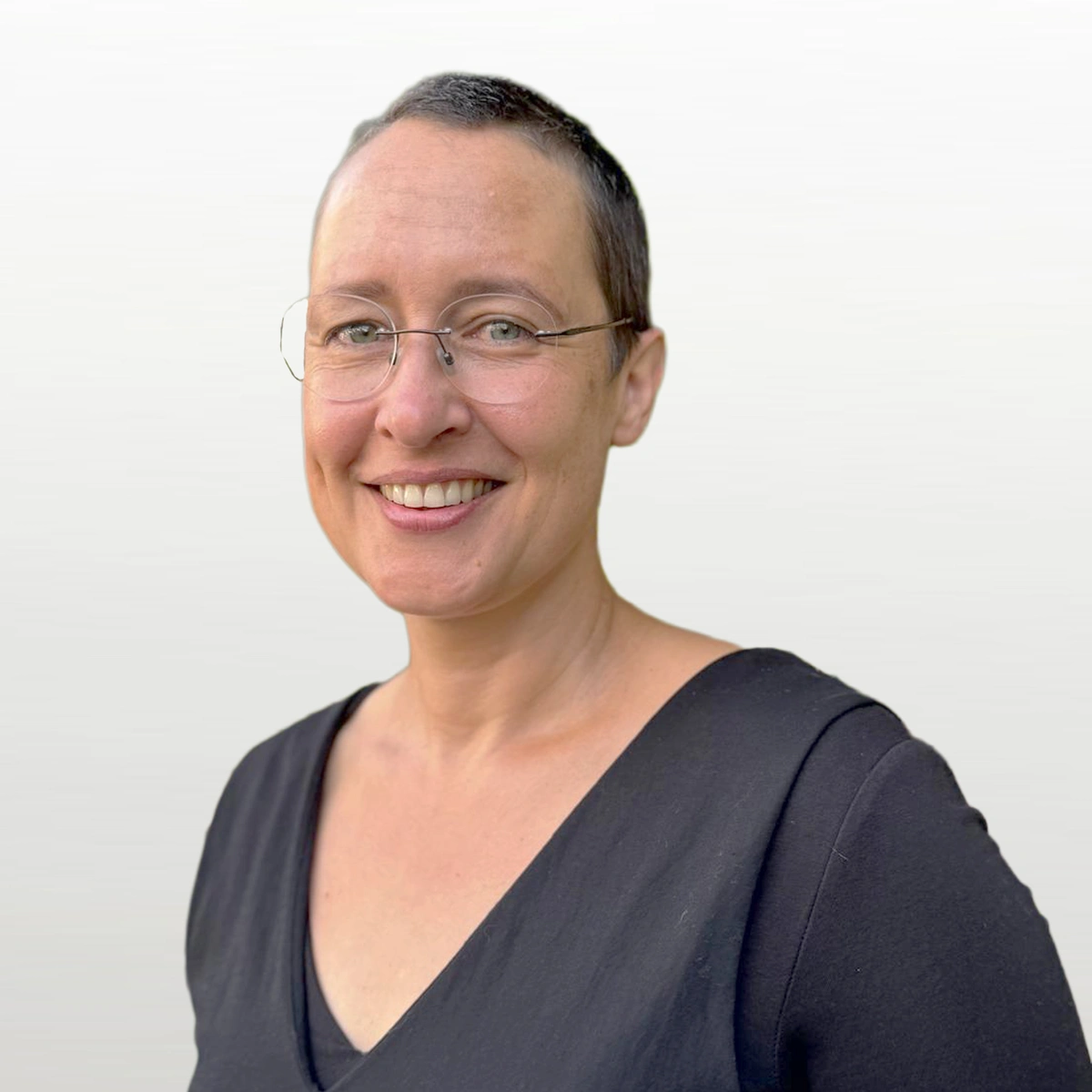 Frau mit kurzen Haaren und einer Brille lächelt freundlich in die Kamera