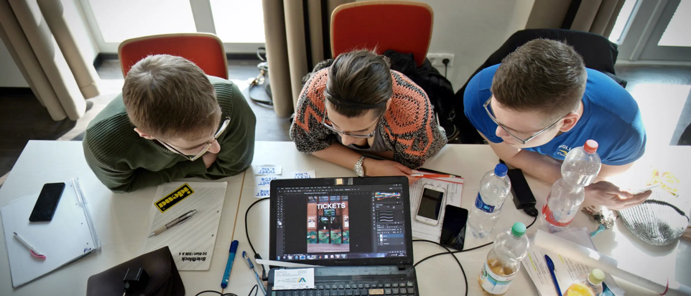 Drei Freiwillige beugen sich über einen Laptop.